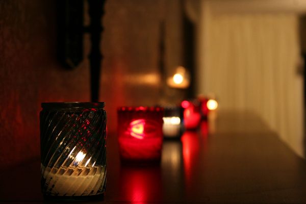 Red and clear votive candles glowing in a darkened church.